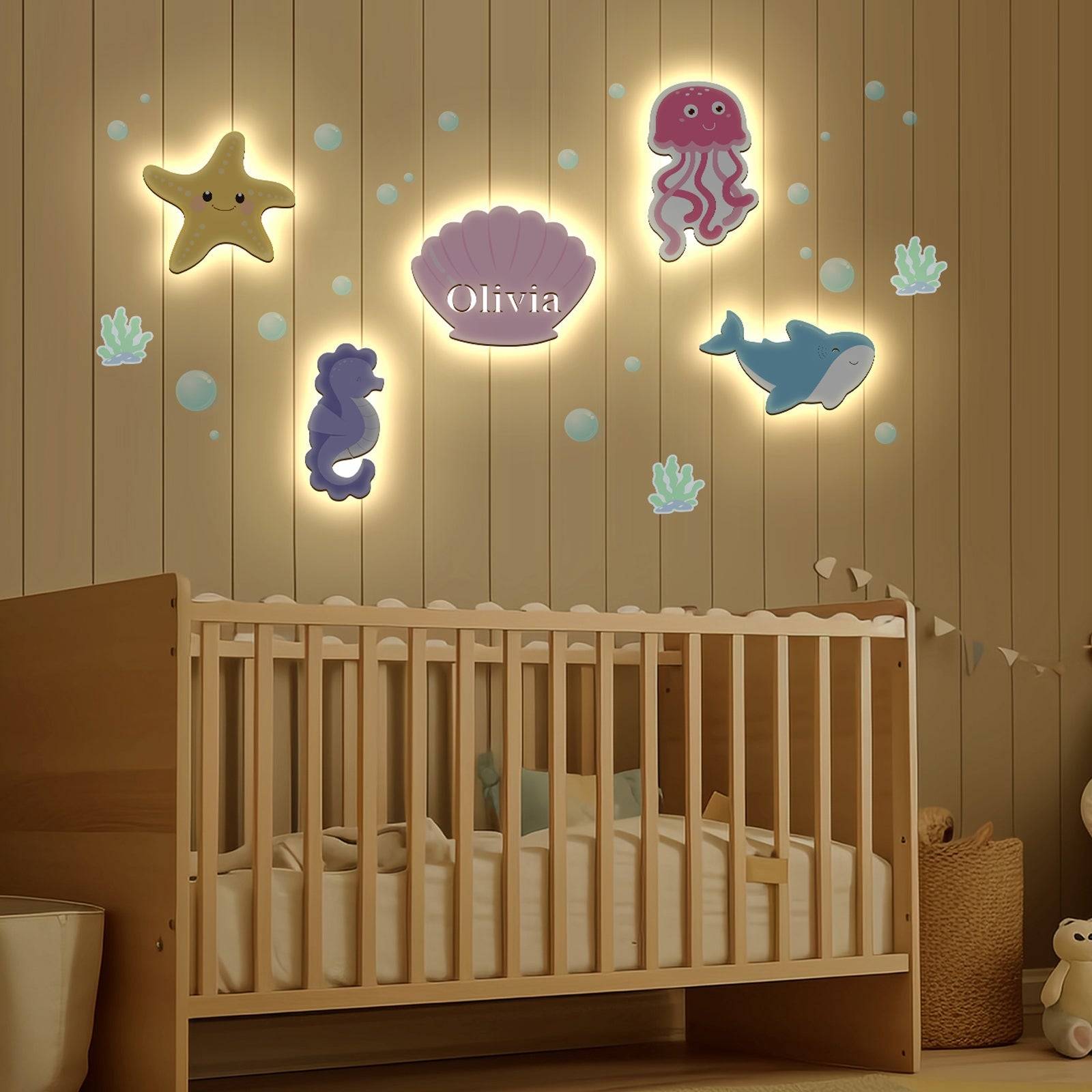Marine-themed personalized wooden wall light set illuminating a baby's room with colorful sea creatures.