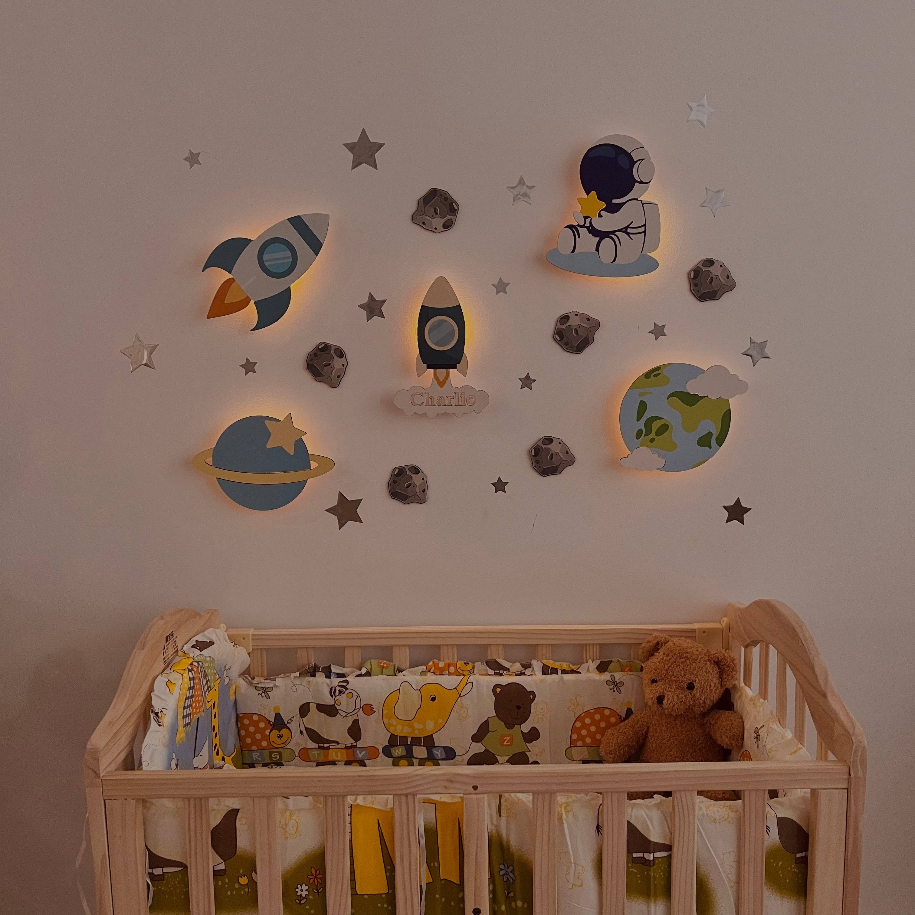 Personalized wooden space model wall lights in a baby room, featuring rockets and planets, soft glowing light.