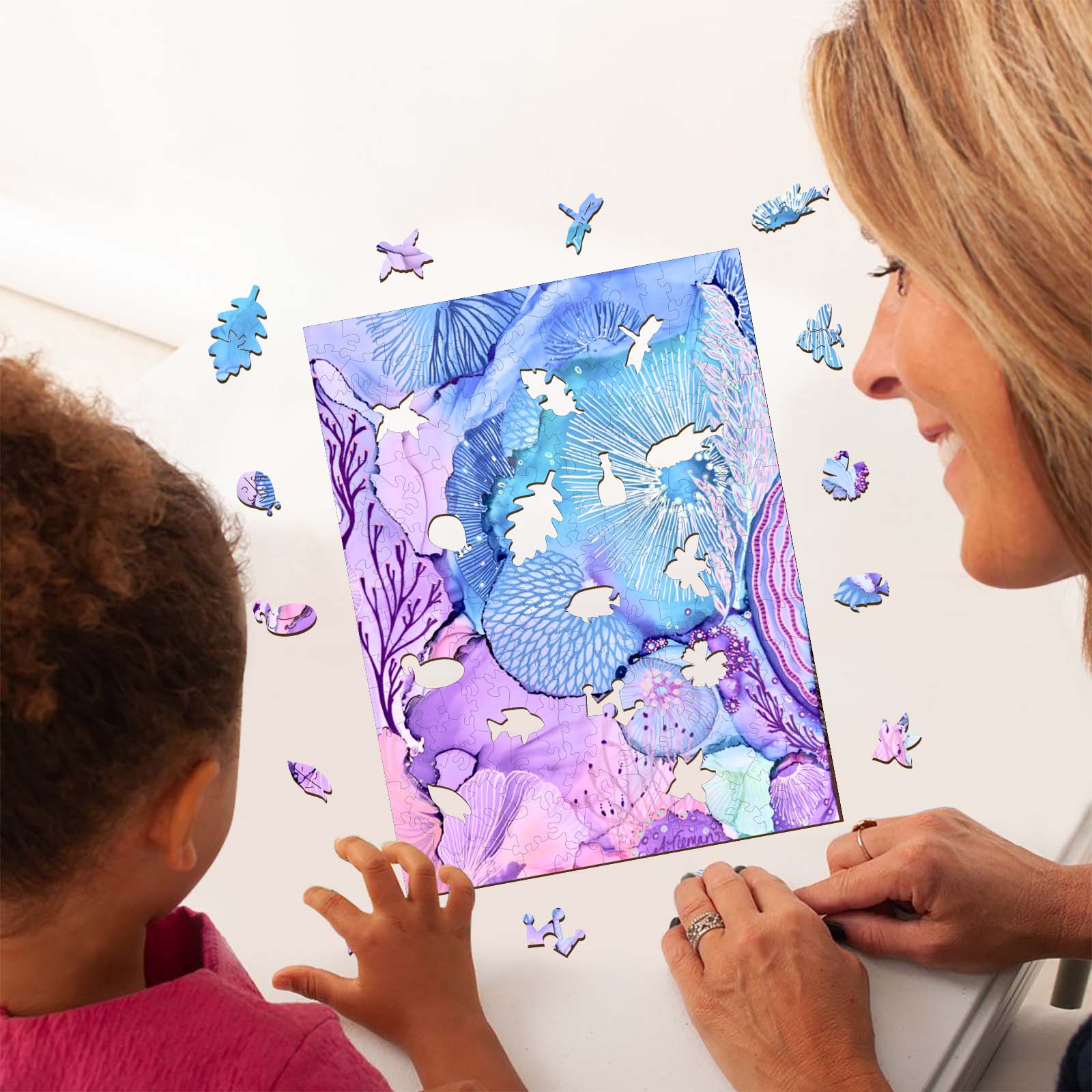 A woman and child assembling a colorful undersea puzzle showcasing vibrant coral and fish designs.