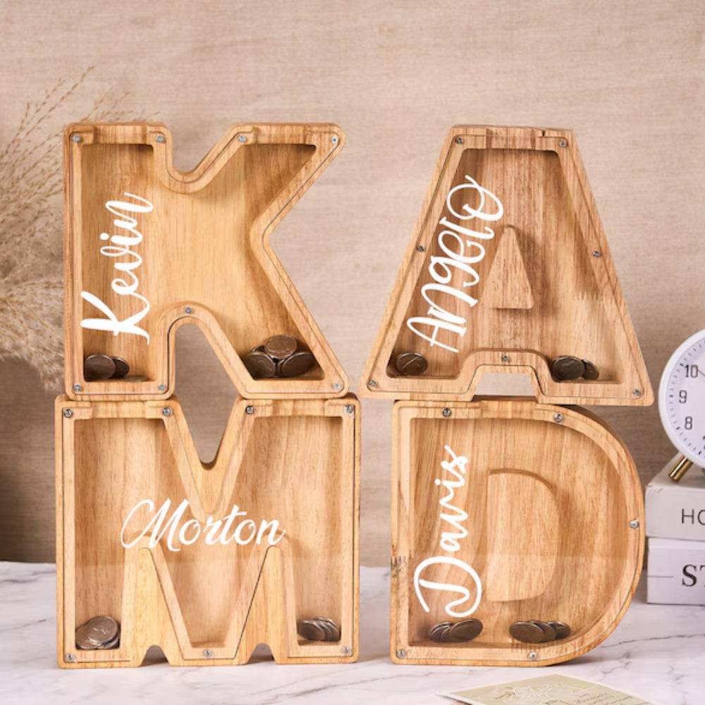 Personalized wooden letter piggy bank displaying names Kevin, Angelo, Morton, and Davis with coins inserted.