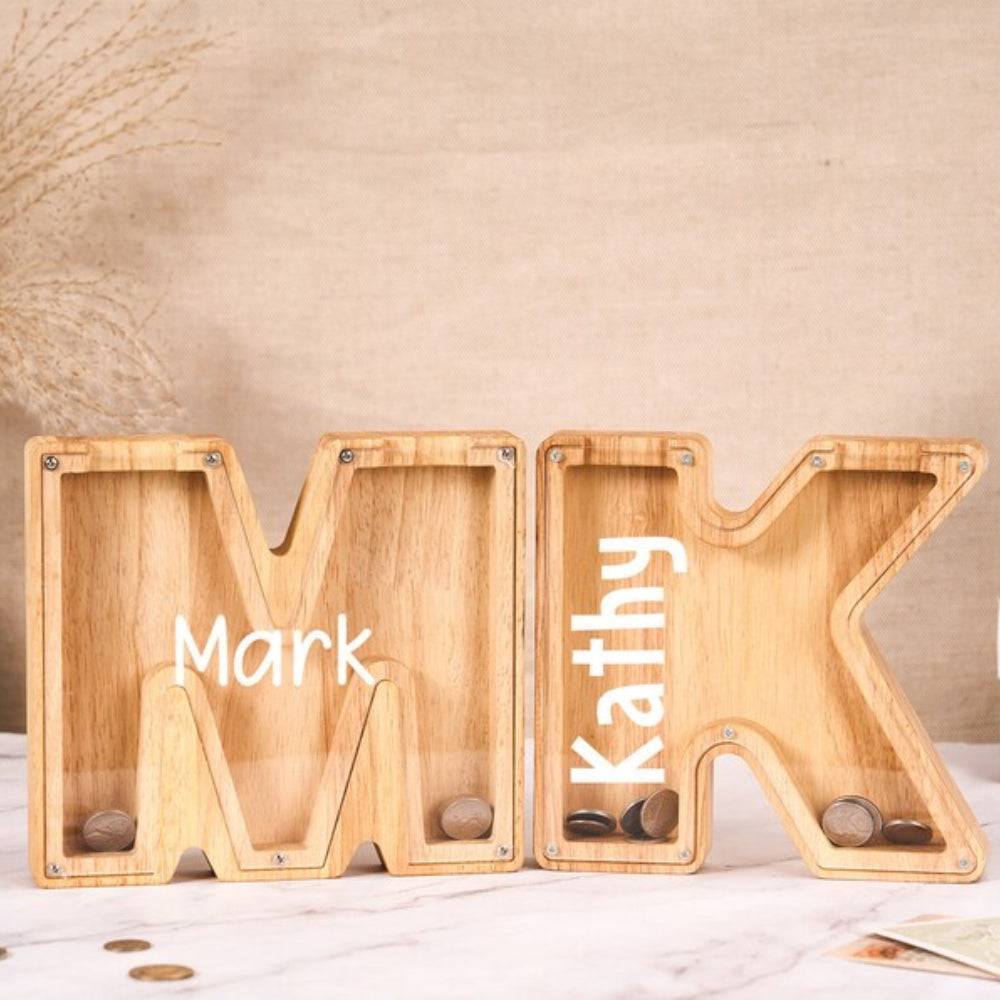 Personalized wooden letter piggy banks for kids, featuring names Mark and Kathy, ideal for teaching savings.